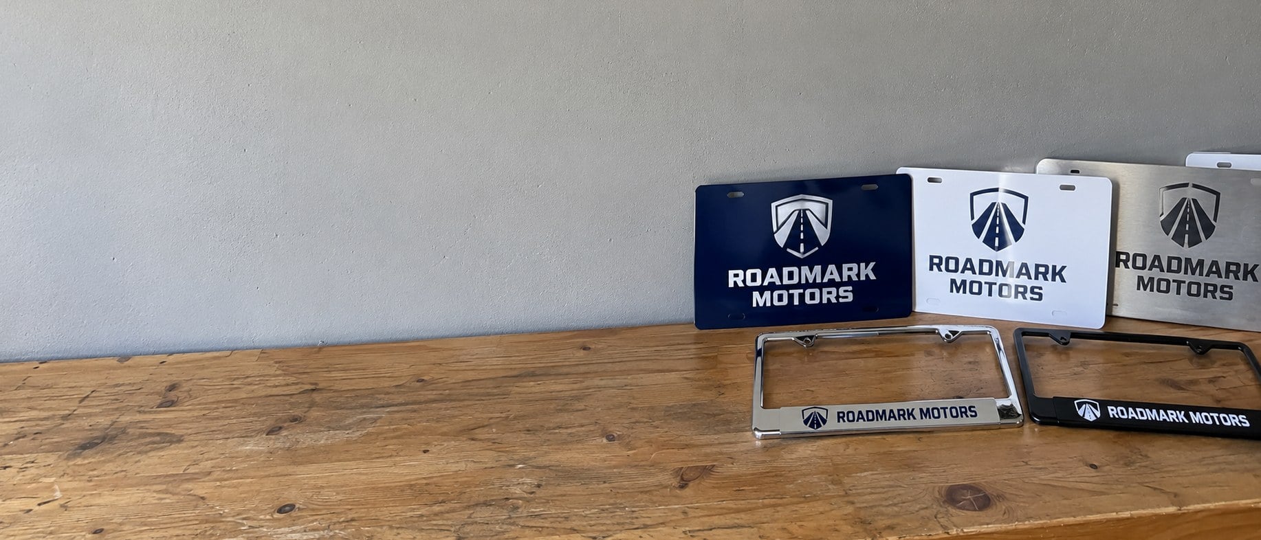 Branded novelty license plates and plate frames laid out on a workbench